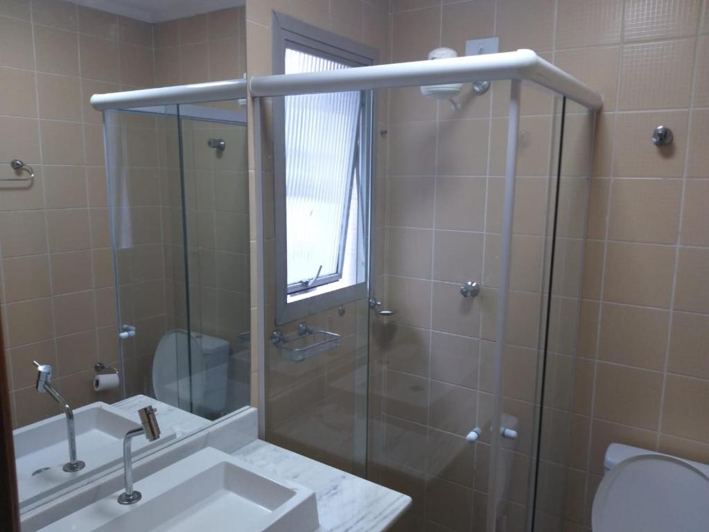ein Badezimmer mit Dusche, Waschbecken und Toilette in der Unterkunft Apartamento para alugar - temporada in Guarujá