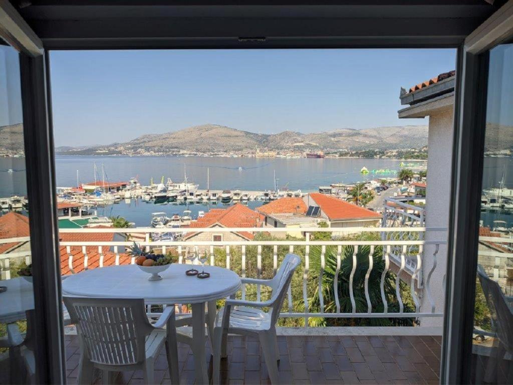 uma varanda com uma mesa e cadeiras e vista para um porto em Apartments Biserka - 50 m from beach em Trogir