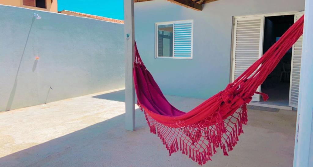 a red hammock hanging outside of a house at Casa em São Miguel dos milagres. in São Miguel dos Milagres