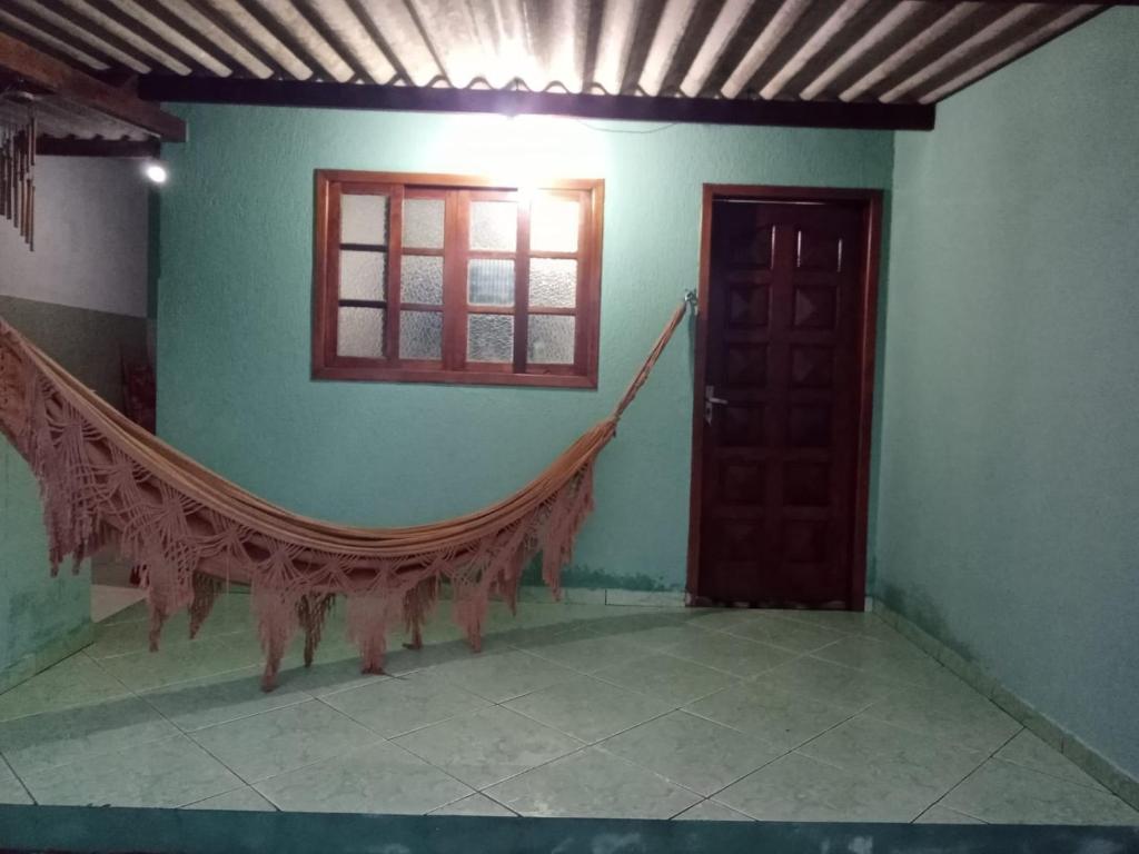 a room with a window and a hammock on the wall at Casa pé na areia in Ubatuba