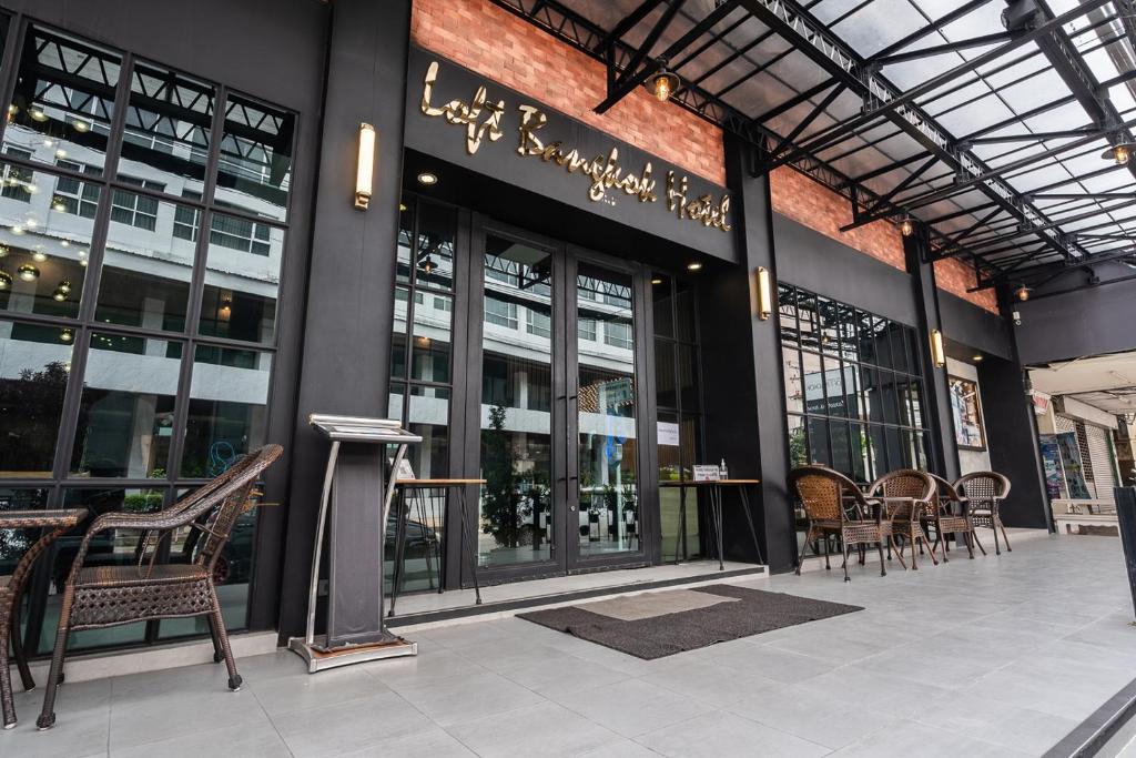 バンコクにあるLoft Bangkok Hotelの正面に椅子とテーブルがある建物