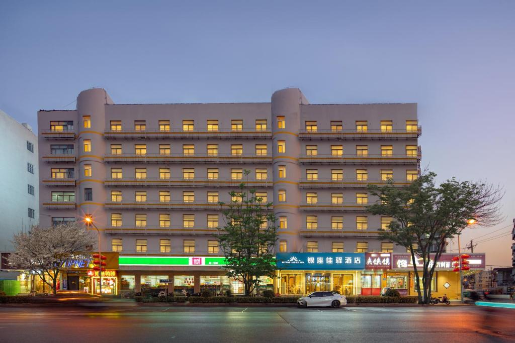 a large building with a car parked in front of it at 银座佳驿济南大明湖火车站店 in Jinan