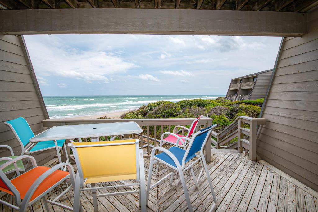 een balkon met stoelen en een tafel met uitzicht op de oceaan bij Ocean Grove in Pine Knoll Shores