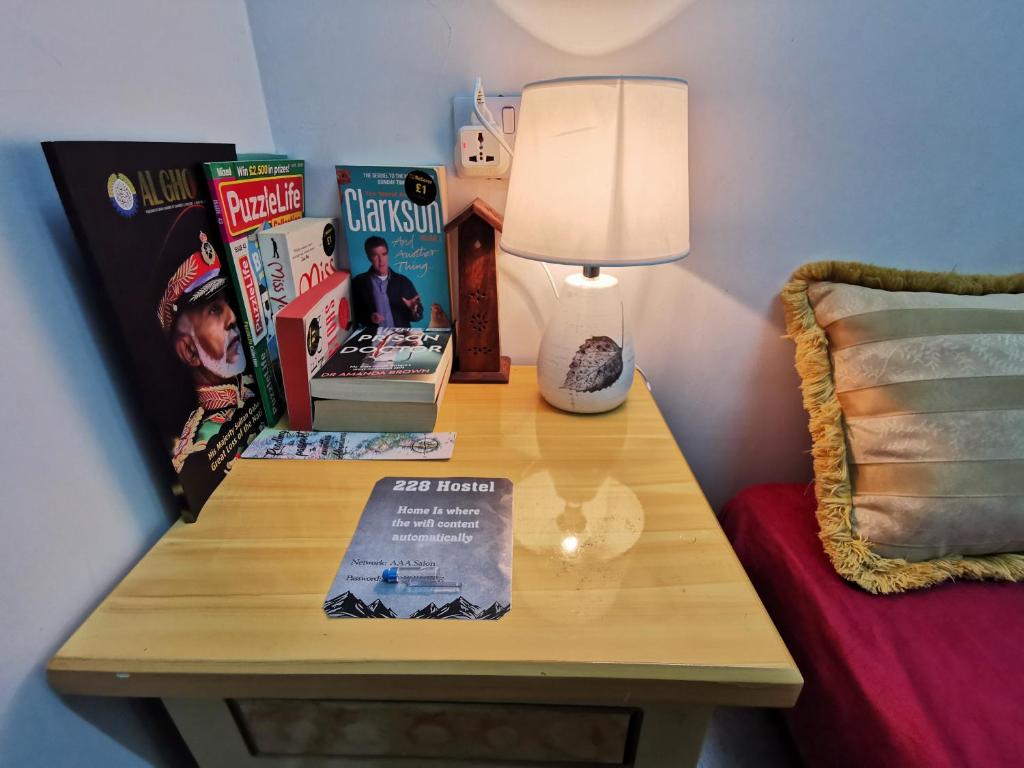 228Hostel في الحمرا: طاولة مع كتب ومصباح فوق سرير