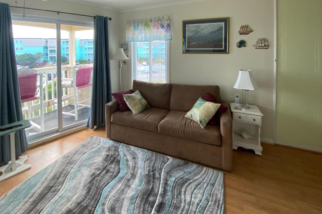 ein Wohnzimmer mit einem braunen Sofa und einem Fenster in der Unterkunft A Place At The Beach VI in Atlantic Beach