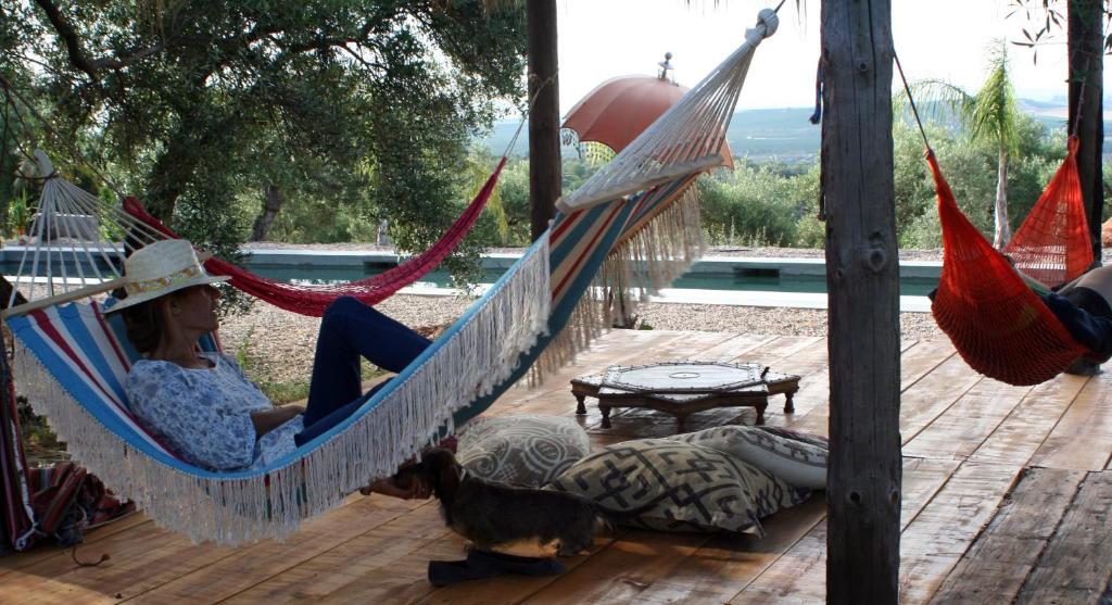 a woman sitting in a hammock on a deck at Casa las Marias in Hornachuelos