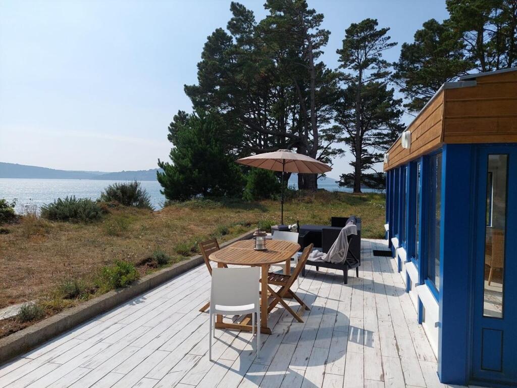 a patio with a table and chairs and an umbrella at Holiday home in a secluded location surrounded by the sea, Hanvec in Hanvec