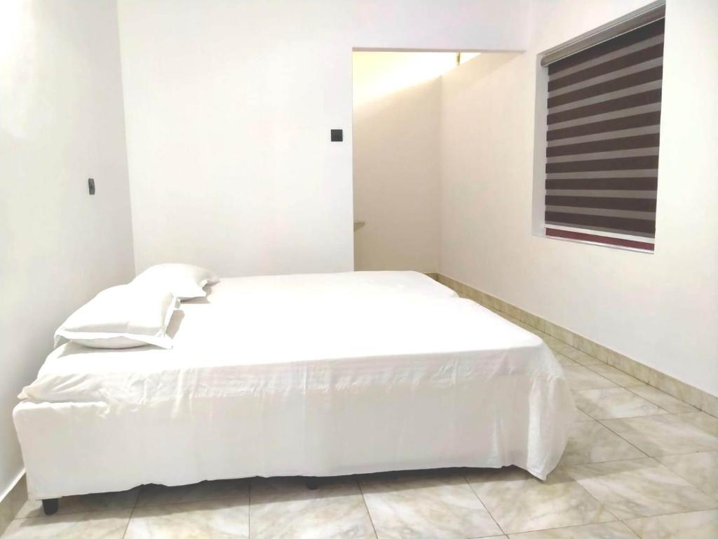 a white bedroom with a white bed and a window at Thekkumpuram Tourist Home in Malappuram