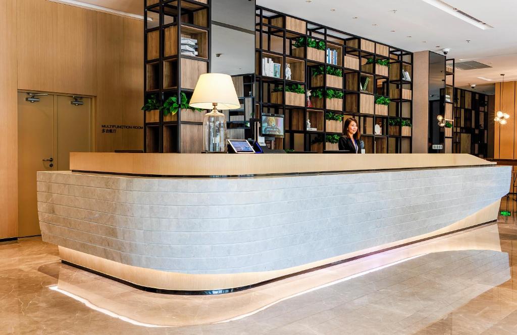 a woman standing behind a counter in a lobby at Eature Residences Lingang in Shanghai