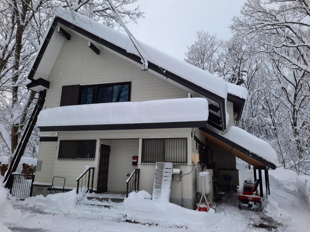 Una casa con nieve en el techo. en Powder Peak Misorano Free courtesy car en Hakuba