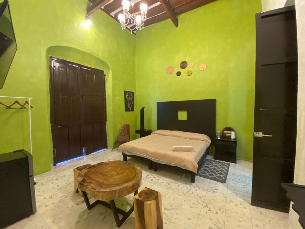 - une chambre avec des murs verts, un lit et une table dans l'établissement Hotel Edzna, à Campeche