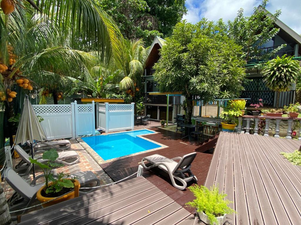 un patio trasero con piscina y una casa en Mer Riviere Self Catering Apartment, en Beau Vallon