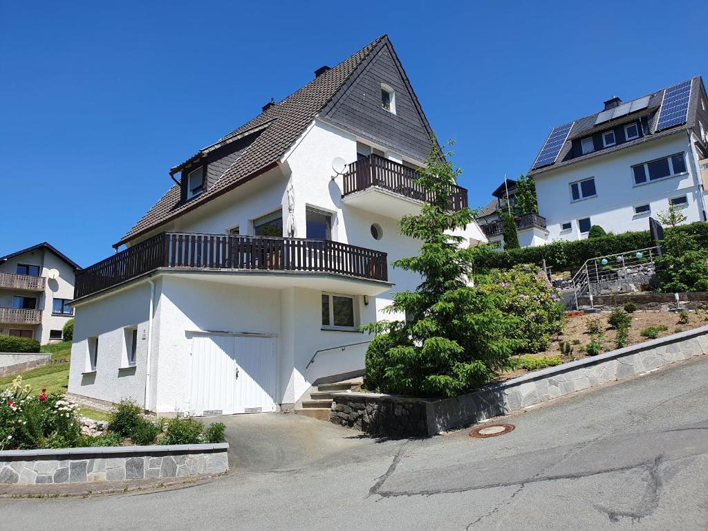 a white house with a balcony on a street at Ferienhaus Junge Ruhr in Olsberg