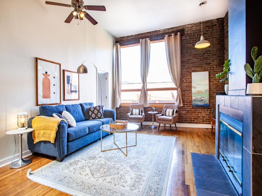 a living room with a blue couch and a brick wall at Spacious Old City Loft in Knoxville