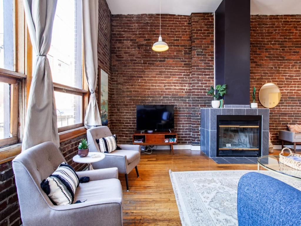 ein Wohnzimmer mit einer Ziegelwand und einem Kamin in der Unterkunft Spacious Old City Loft in Knoxville