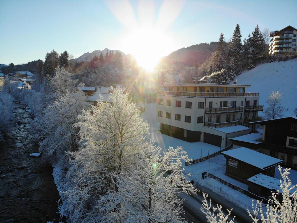 a building in the snow with the sun in the background at Boutique-Apartments Seminarium F5 Fieberbrunn in Fieberbrunn