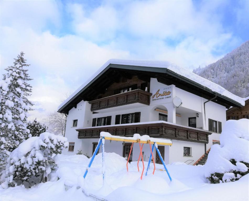 un lodge de esquí con un columpio en la nieve en Ferienwohnung Anita, en Sankt Gallenkirch