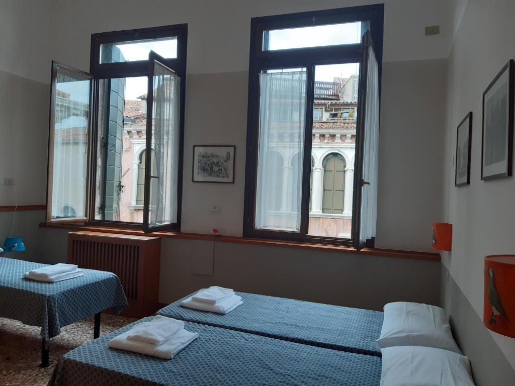 two beds in a room with two windows at Foresteria Valdese Venezia in Venice