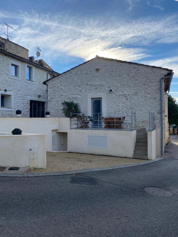 - un bâtiment en briques blanches avec un portail et un balcon dans l'établissement Au bon logis Luberon 50m2, à Cheval-Blanc