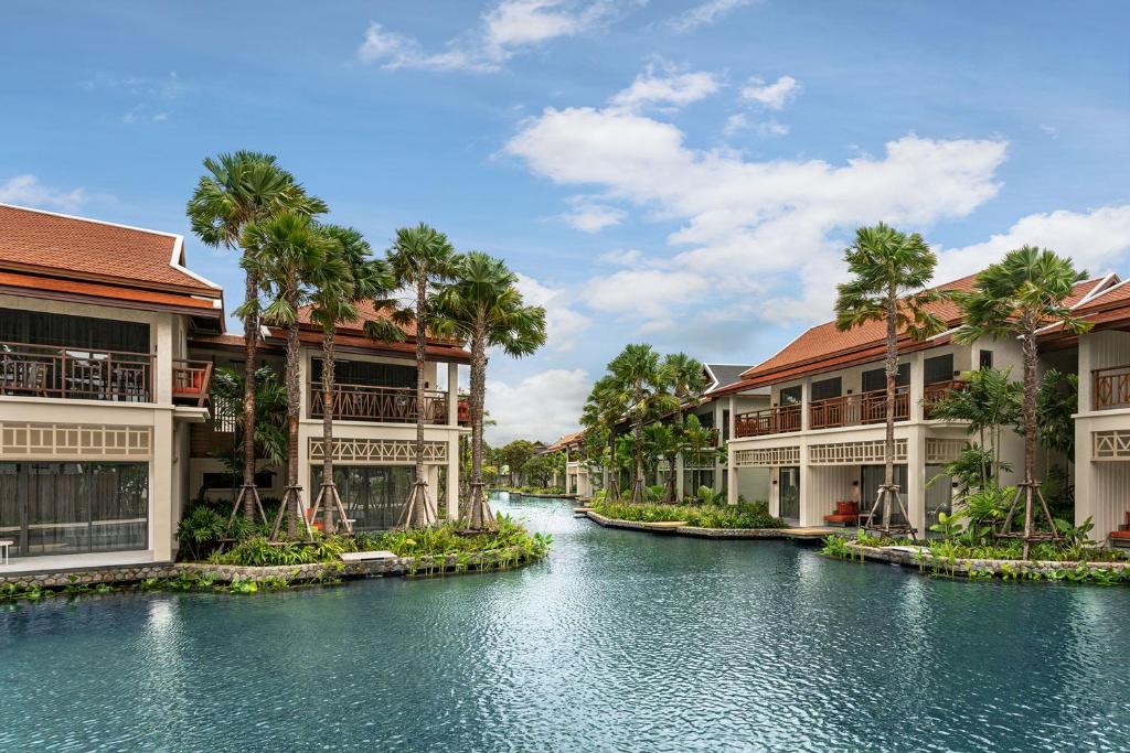 a river between two buildings with palm trees at Grand Mercure Khao Lak Bangsak in Khao Lak