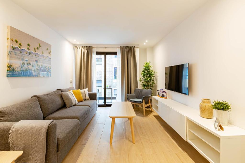 sala de estar con sofá y TV en Apartamentos Deluxe Strada, en Las Palmas de Gran Canaria