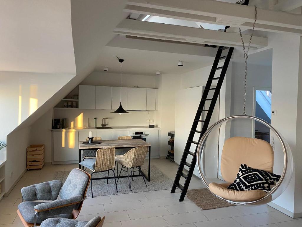 a living room with a ladder and chairs and a kitchen at Ferienwohnung an der Rosenterrasse - Meerblick in Glücksburg