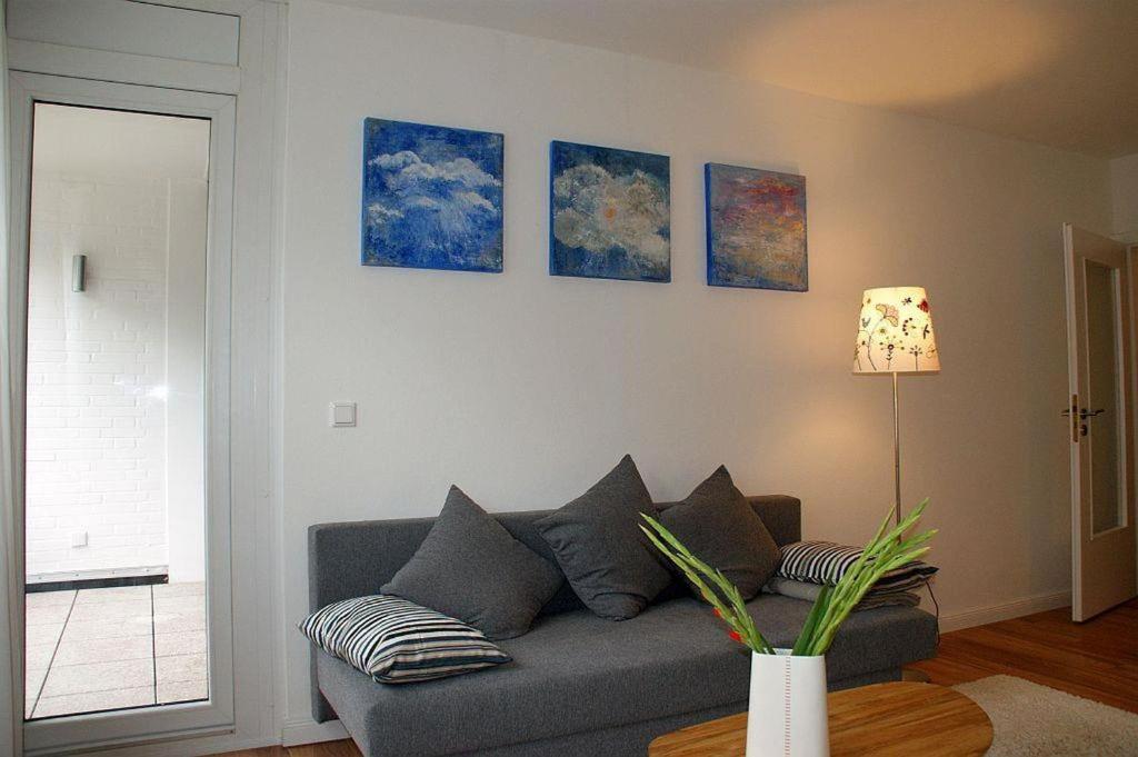 a living room with a couch and paintings on the wall at Ferienwohnung Fördeglück in Glücksburg