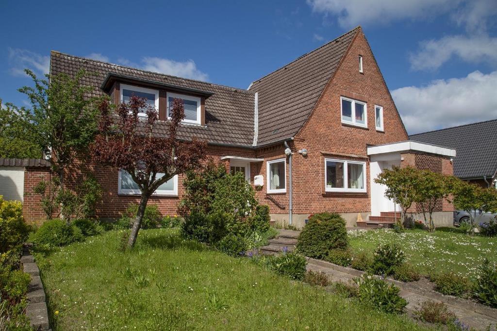 a brick house with a tree in the yard at Feddersen's Ferienwohnung in Harrislee