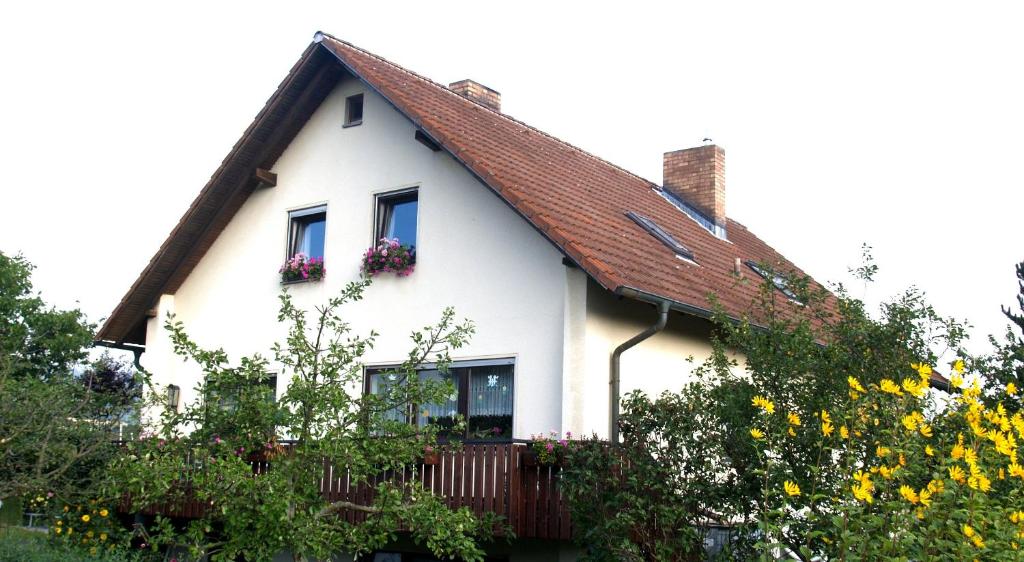 a white house with a red roof and flowers at Ferienwohnung Haus Silvia in Fladungen
