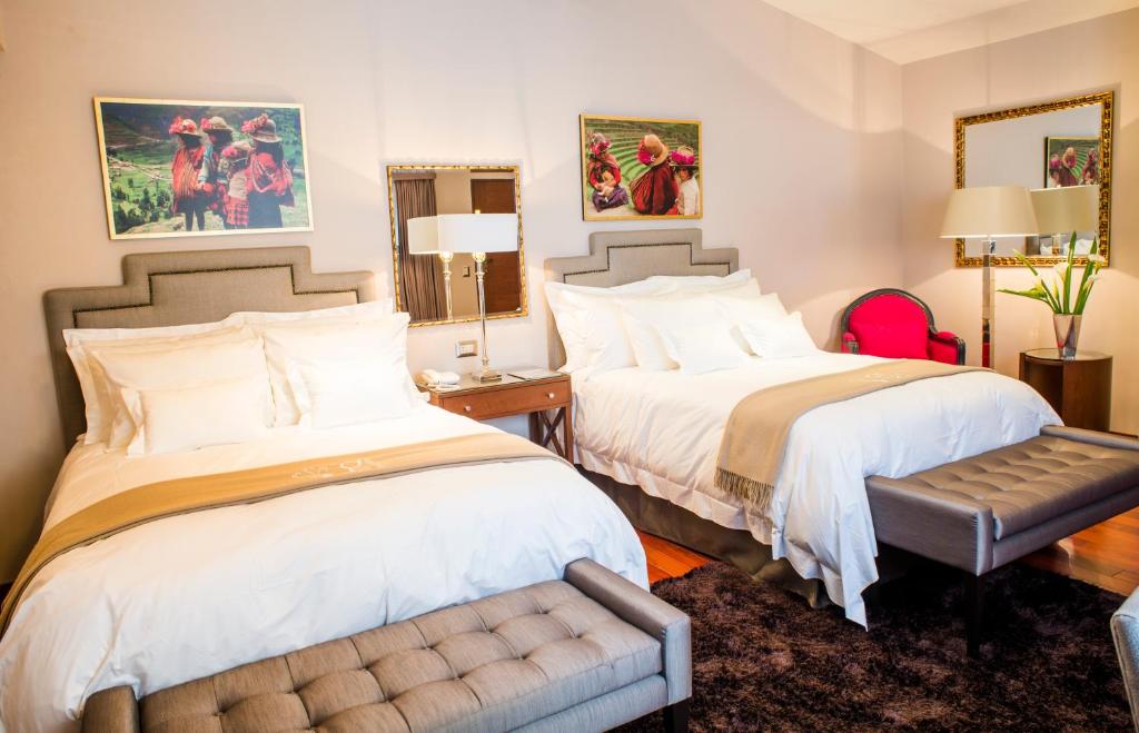 una habitación de hotel con 2 camas y un banco en Atiq Boutique Hotel, en Cusco