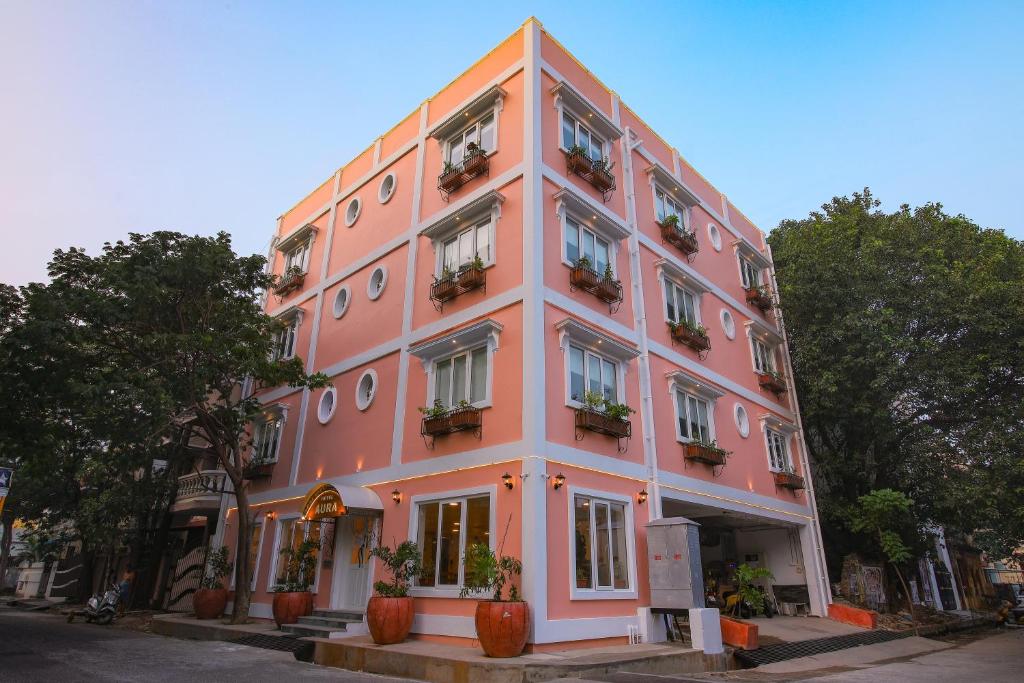 um edifício cor-de-rosa com vasos de plantas à sua frente em AURA HOTEL em Pondicherry