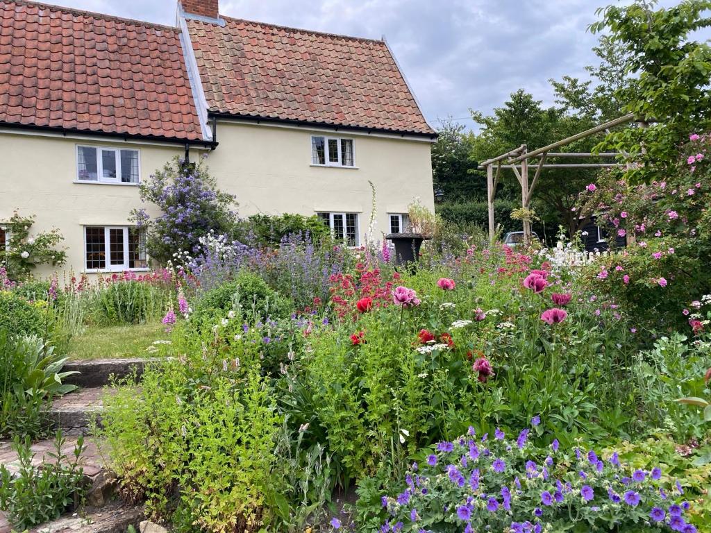 a garden in front of a house with flowers at Mulleys Cottage (Bed and Breakfast) in Westleton