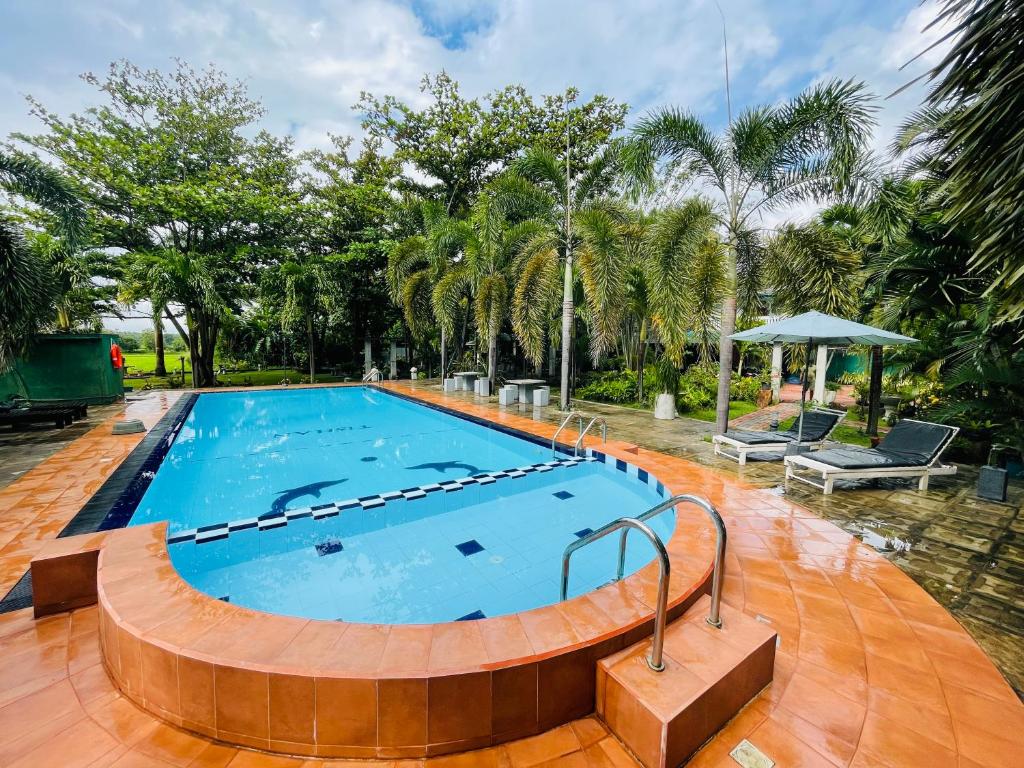 a large swimming pool with a wooden floor and trees at Tishan Holiday Resort in Polonnaruwa