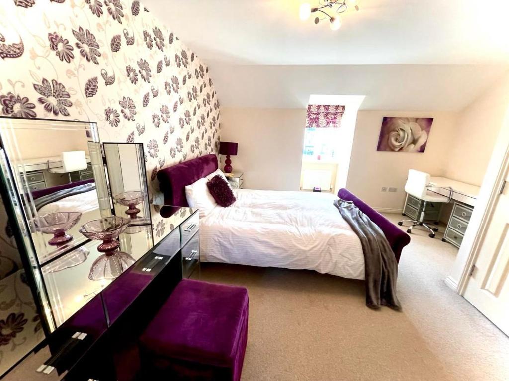 a bedroom with a bed with purple furniture and a mirror at Lakeside Stylish 3 Bedroom House in Grays Thurrock