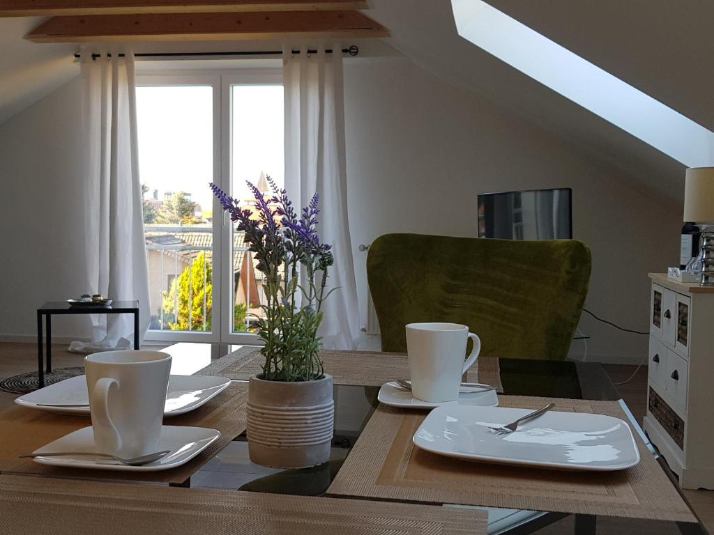 una mesa de comedor con platos blancos y flores. en Ferienwohnung Berliner Straße en Schloß Holte-Stukenbrock