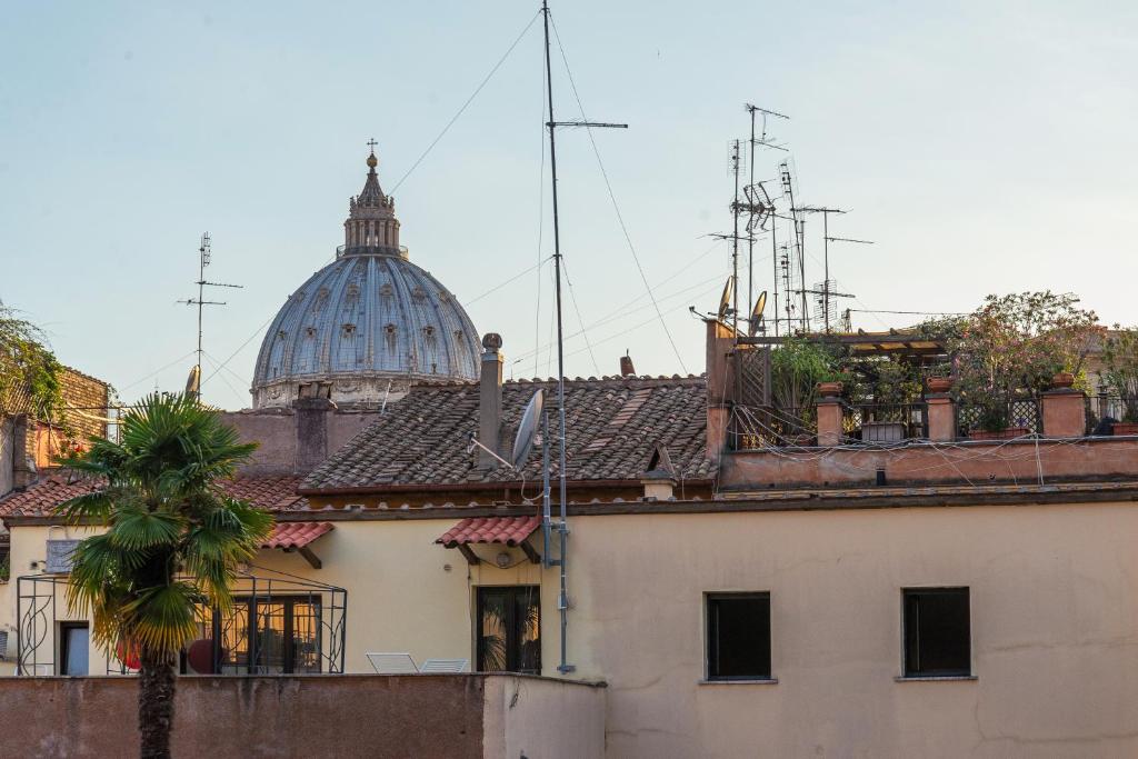 um edifício com uma cúpula ao fundo com uma palmeira em La Porta Rossa di Borgo - Vatican Luxury Suite em Roma