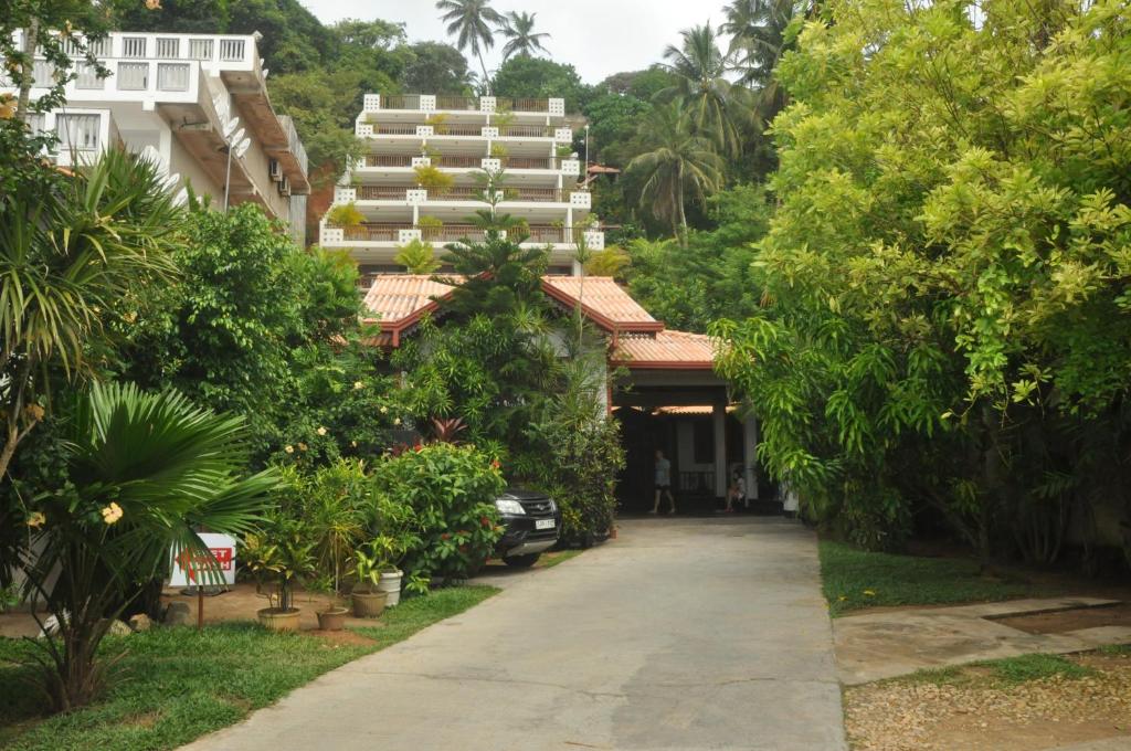 una entrada que conduce a un edificio con árboles y arbustos en Hotel Silan Mo, en Mirissa