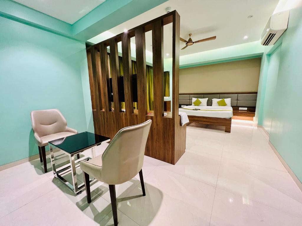Zimmer mit einem Schreibtisch, Stühlen und einem Bett in der Unterkunft Hotel Seven Oaks in Navi Mumbai