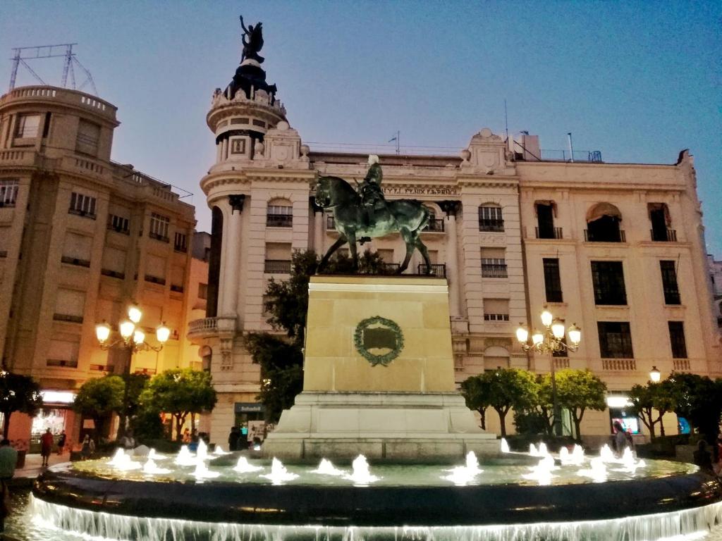una fuente frente a un edificio con una estatua en Apartamento El Duque - Plaza de las Tendillas en Córdoba
