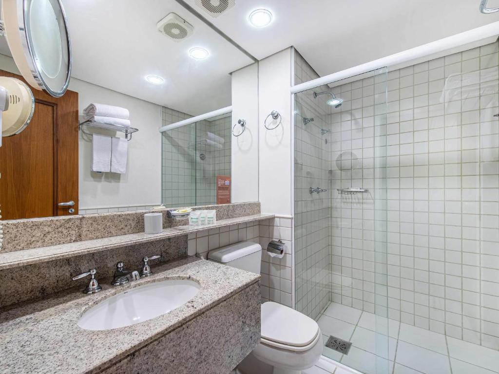 a bathroom with a sink and a toilet and a mirror at Hotel Cassino Tower Campinas Cambuí By Nacional Inn in Campinas