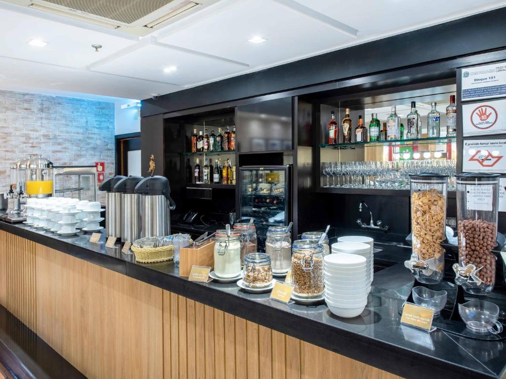 a bar with a counter with food and drinks at Hotel Cassino Tower Campinas Cambuí By Nacional Inn in Campinas