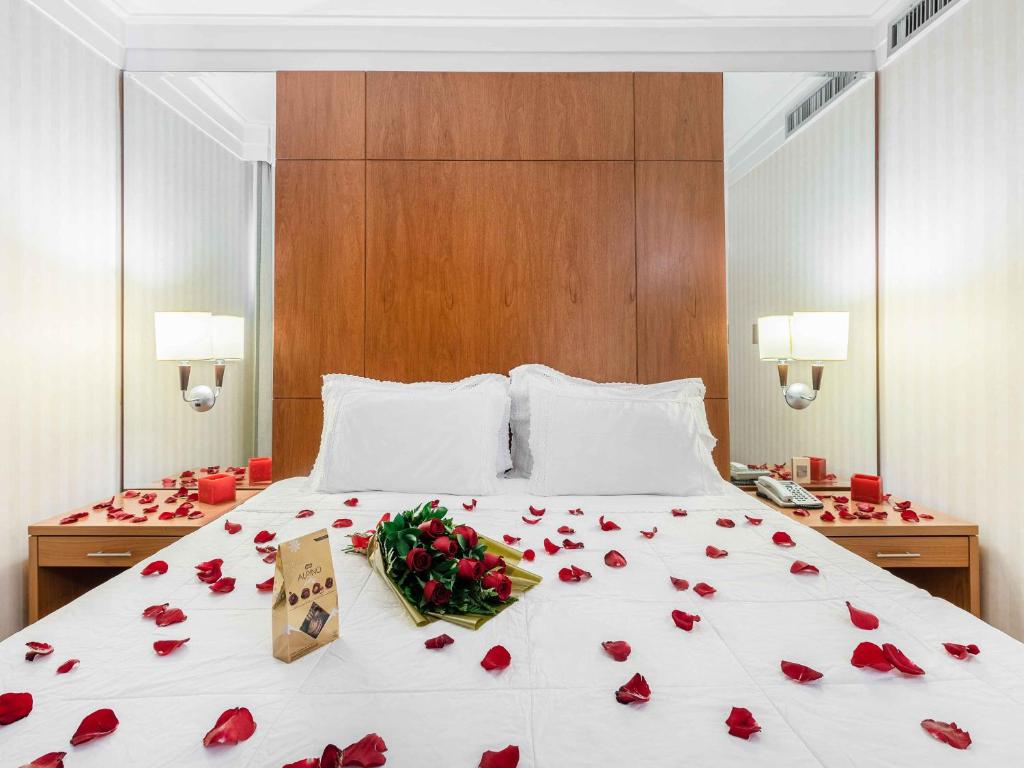 a bed with red rose petals on it at Hotel Cassino Tower Campinas Cambuí By Nacional Inn in Campinas