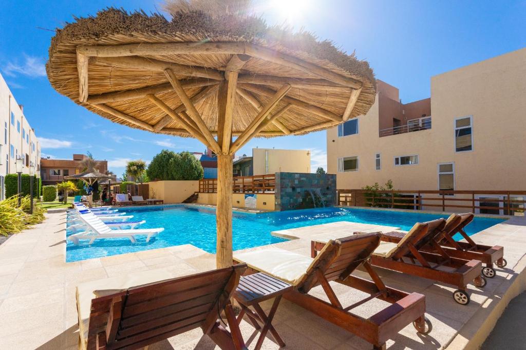 a pool with a table and chairs and a large umbrella at Complejo Tamariscos in Las Grutas