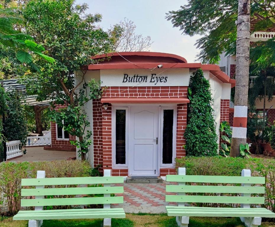 ハイデラバードにあるButton Eyes Resort - Pet friendlyの戸付きの建物前のベンチ2つ