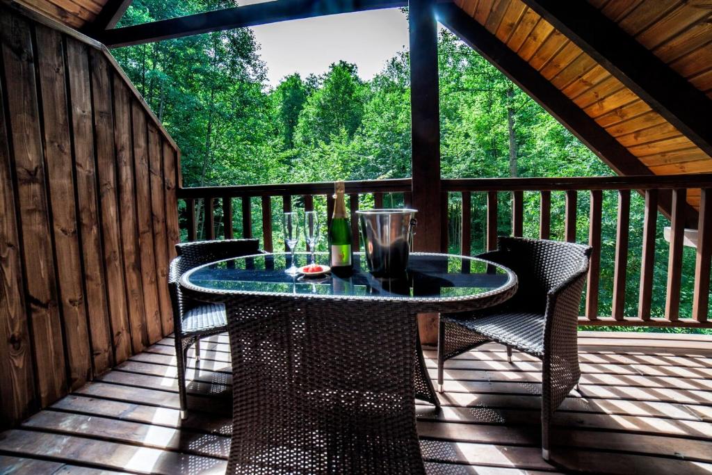 Drewniany balkon z rattanowym stolikiem i dwoma krzesłami z widokiem na las