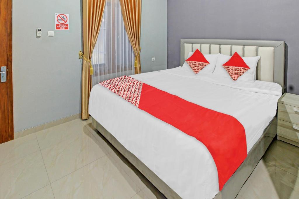 Schlafzimmer mit einem Bett mit einer roten und weißen Decke in der Unterkunft Super OYO 90767 Gm Guest House in Wonogiri