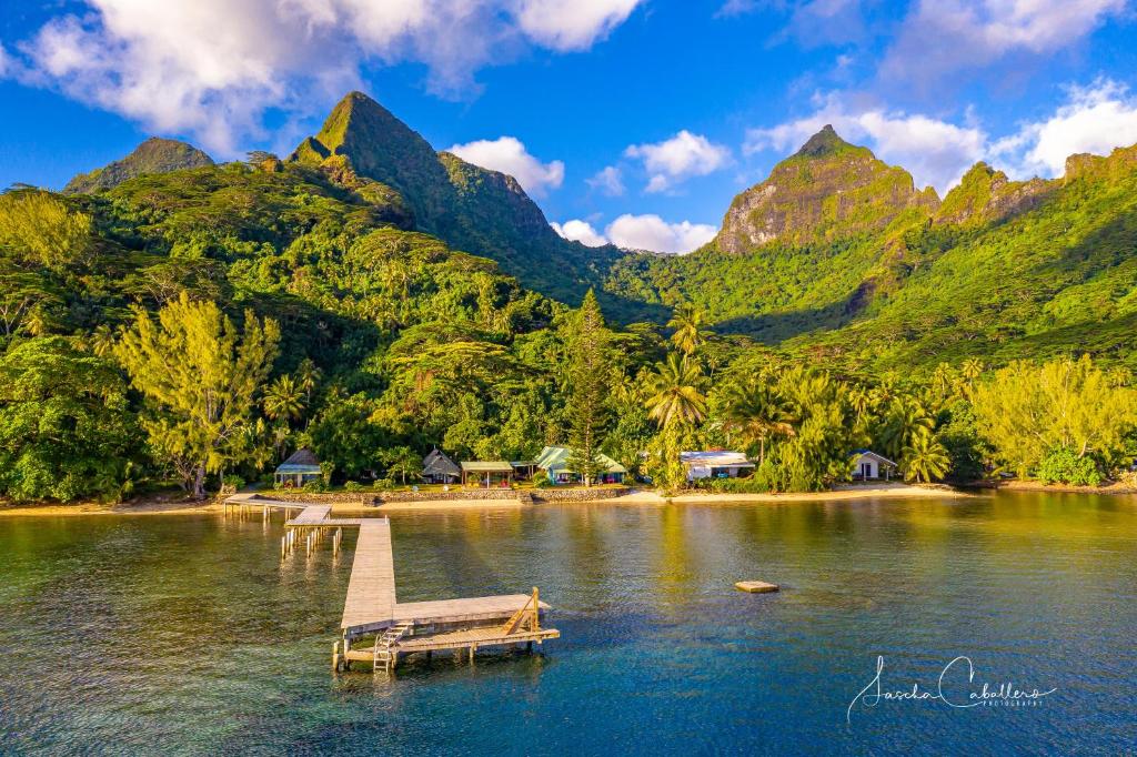 a dock in the middle of a lake with mountains at Linareva Moorea Beach Resort in Haapiti