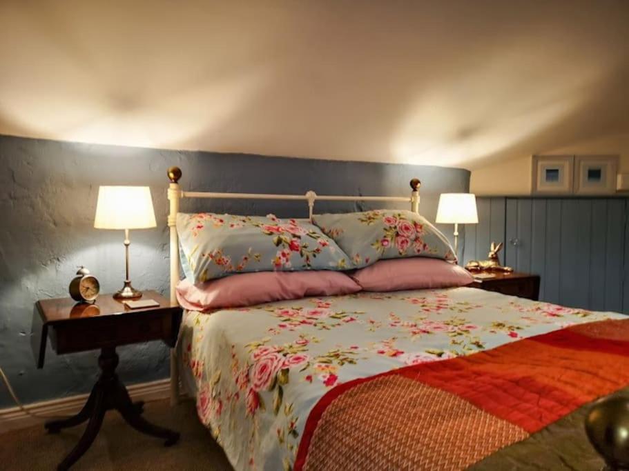 Un dormitorio con una cama con flores. en Riverside Cottage at Logwood Mill en Ballyclare