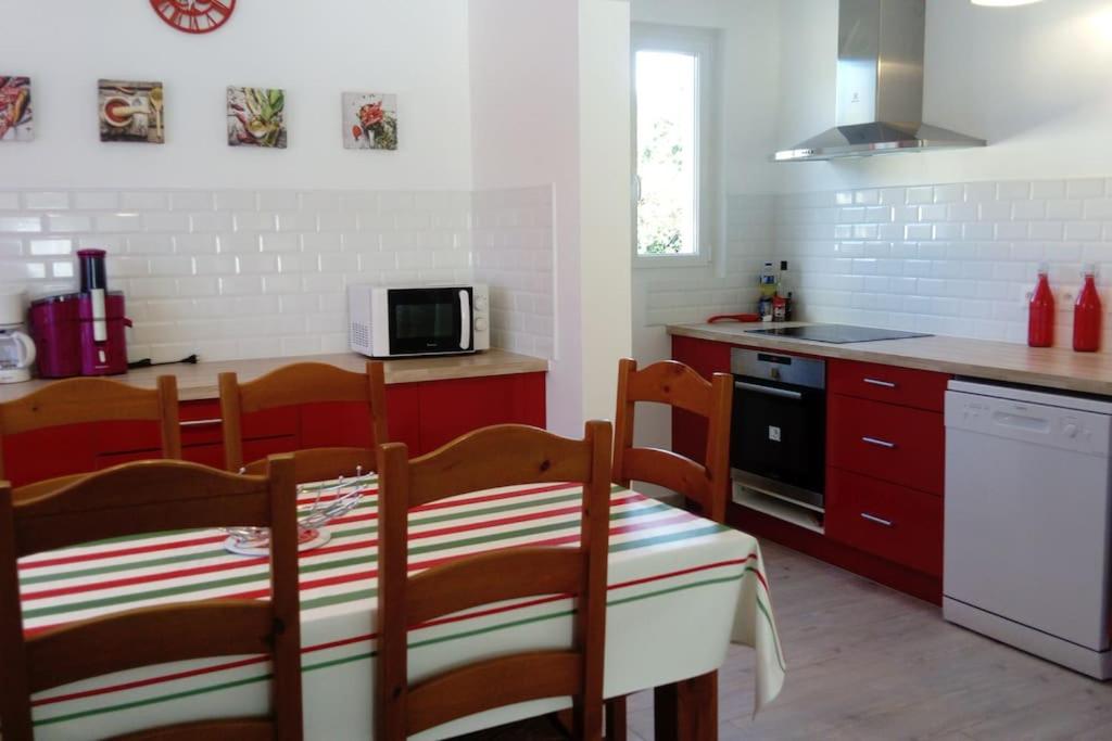 a kitchen with red cabinets and a table and chairs at baratzean in Uhart-Cize
