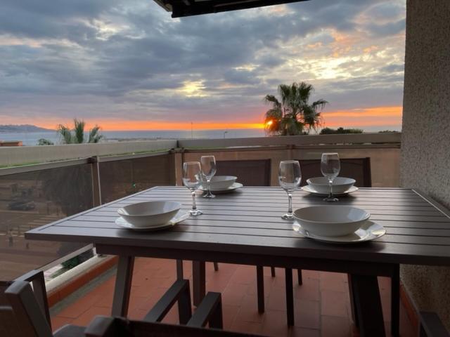 a wooden table with plates and wine glasses on a balcony at PRADO PLAGE in Marseille